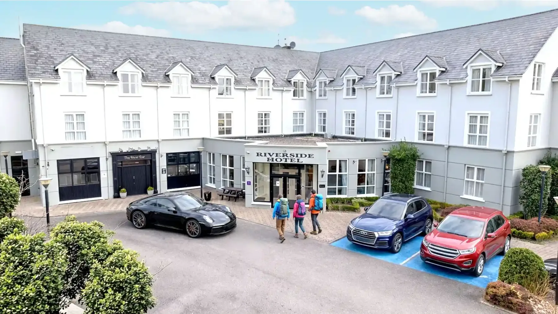 Representative hotel space: A white hotel facade with parked cars in front.