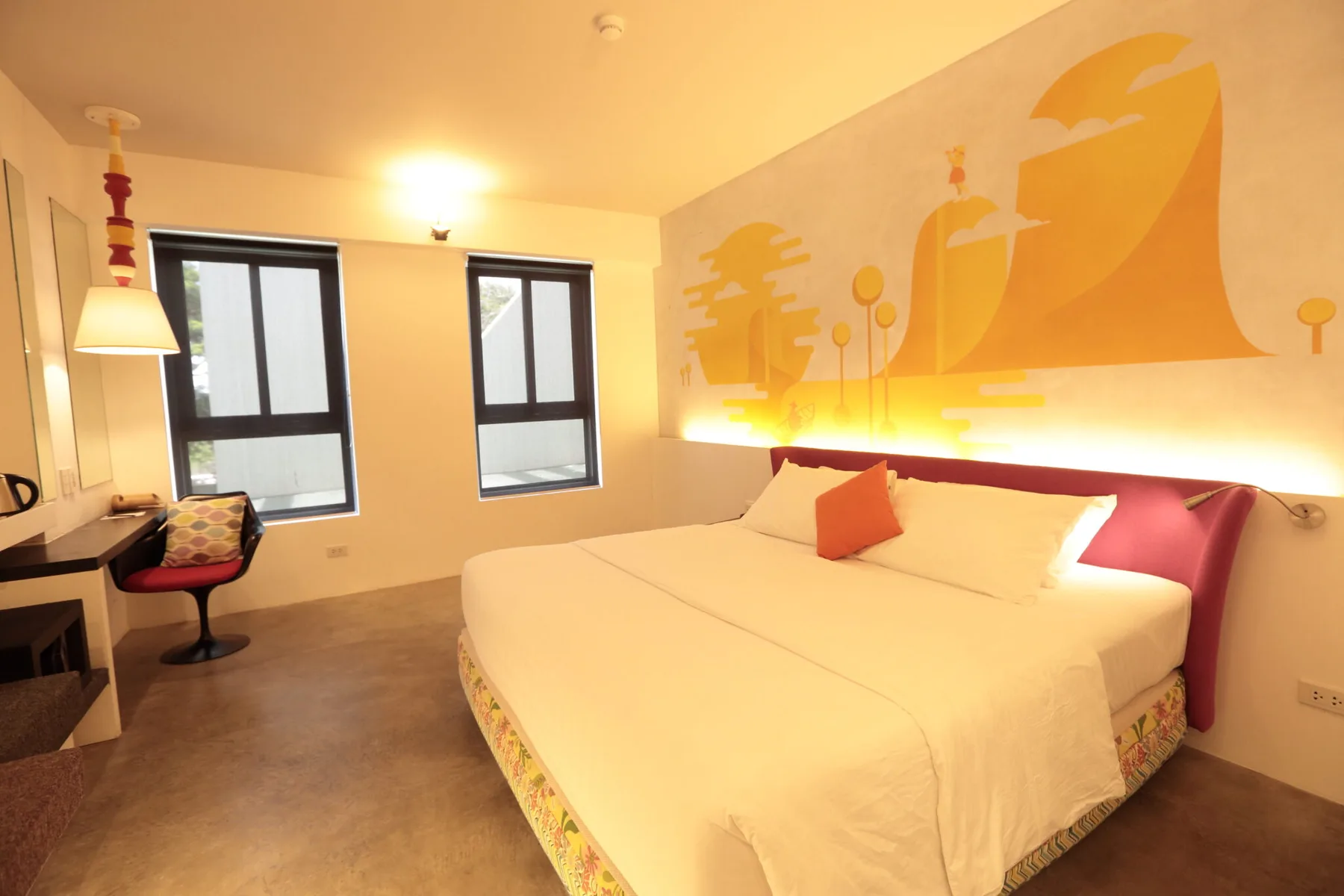 Representative hotel space: A bedroom with a large bed and a colorful mural above the headboard.