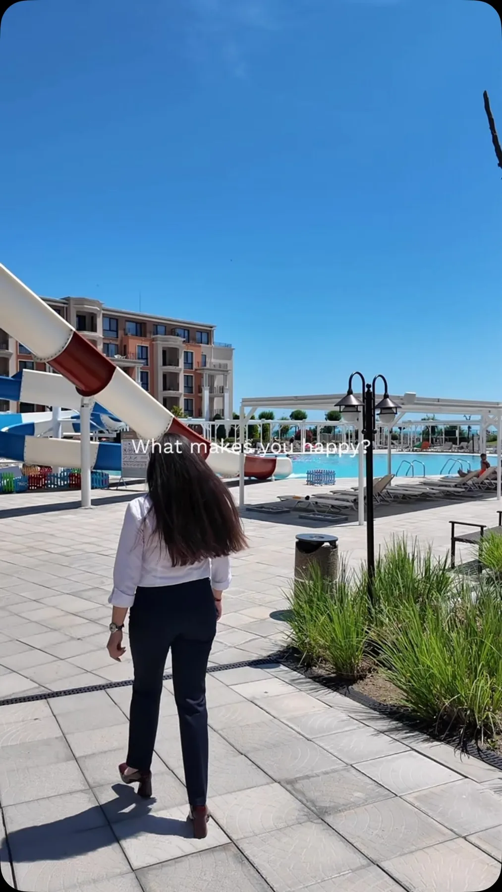 Representative hotel space: A poolside walkway runs beside a swimming pool and a large water slide.