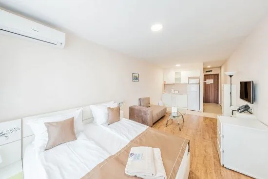 Representative hotel space: A bright bedroom with two beds, a small seating area, and a television.
