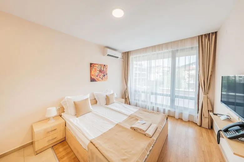 Representative hotel space: A bright hotel bedroom with a bed beside a large curtained window.