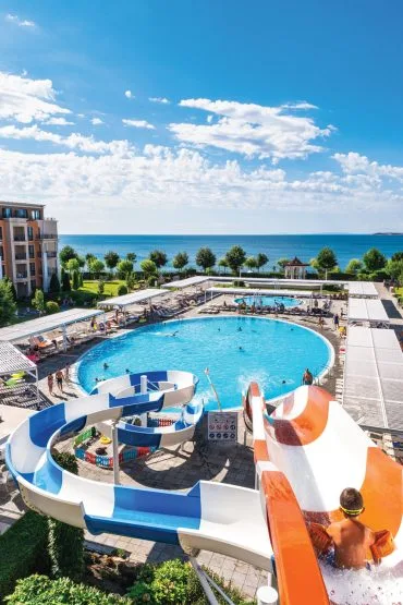 Representative hotel space: An outdoor swimming pool and colorful water slides overlook the sea.