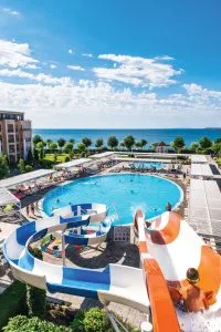 Representative hotel space: A resort pool overlooks the sea, with curved slides beside the water.