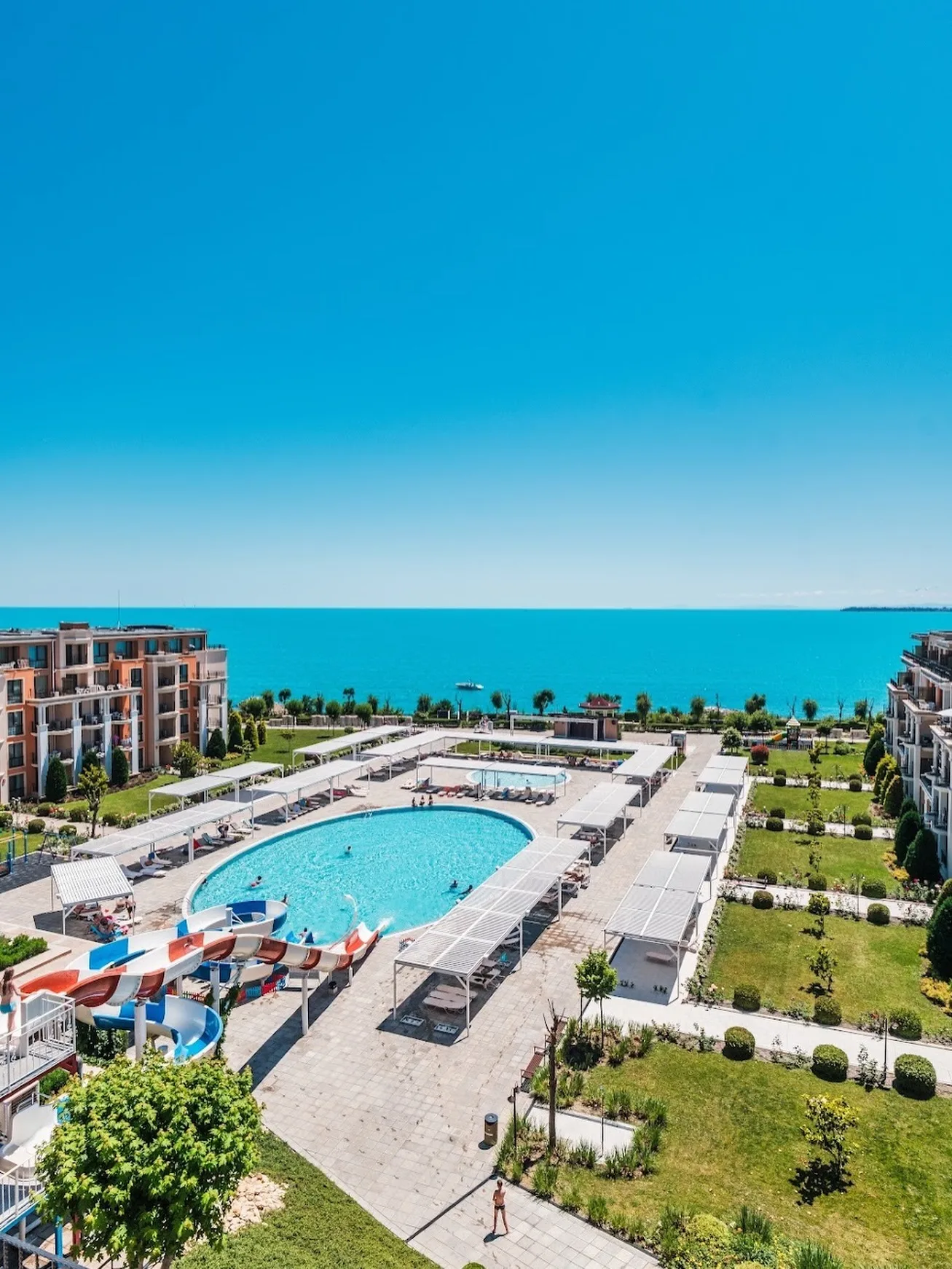 Representative hotel space: A resort pool area with apartment buildings and the sea in the background.