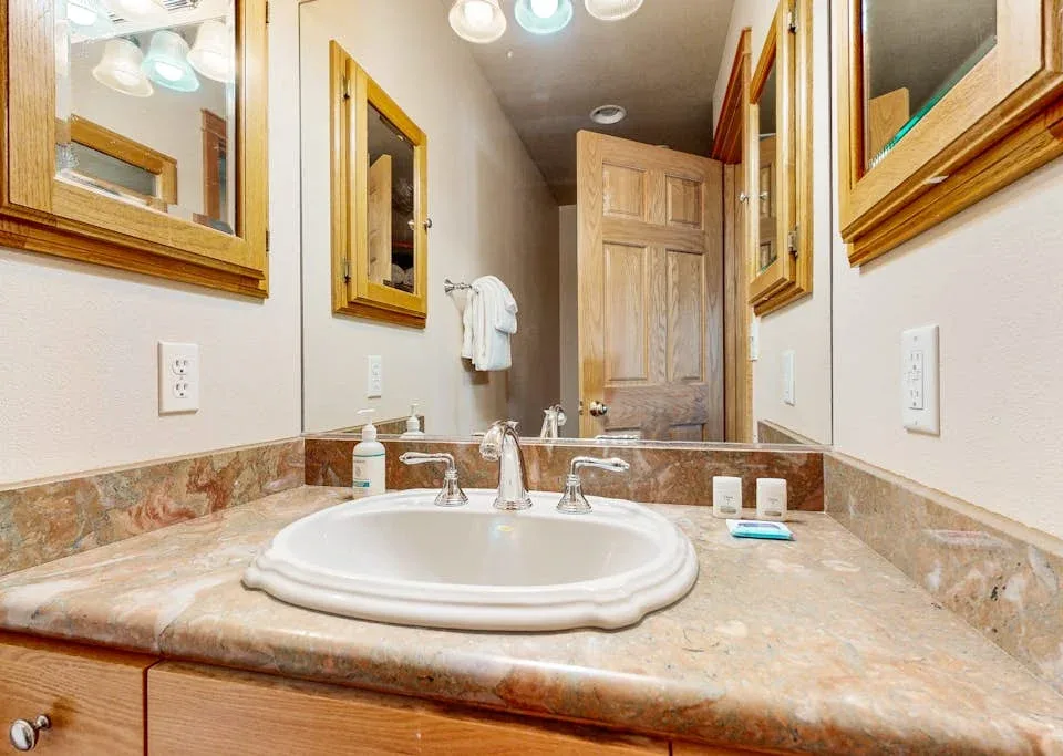 Lavabo de baño con encimera y espejos en la pared.