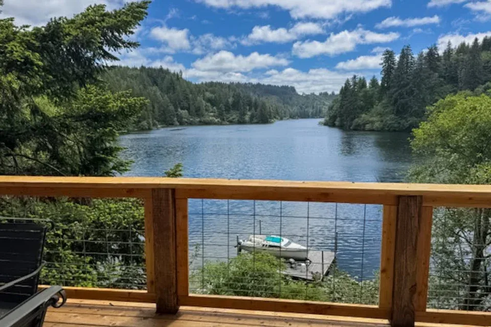 Una terraza de madera da a un lago rodeado de bosque.