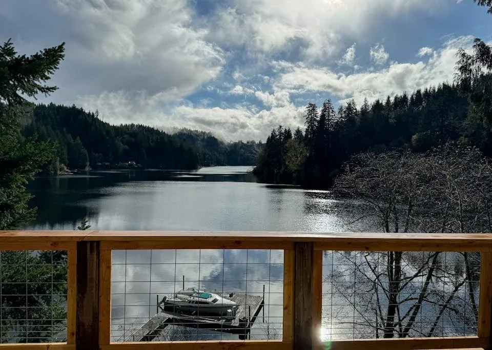 Un lago bordeado de colinas boscosas, visto detrás de una barandilla de madera.