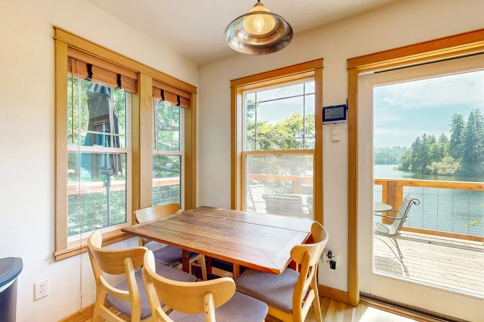Comedor con una mesa de madera junto a ventanas con vista al agua.