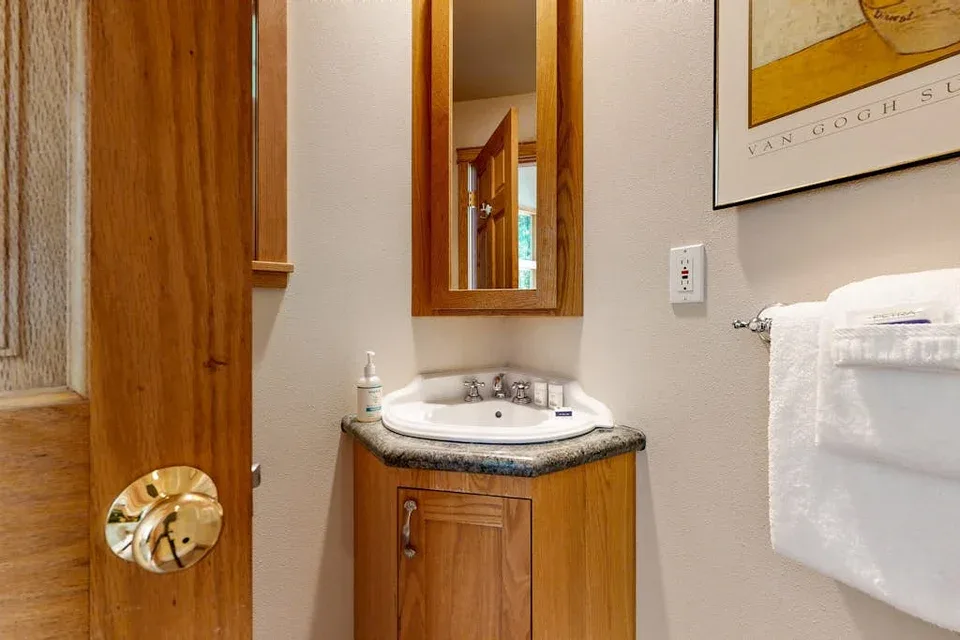 Un lavabo de baño con espejo está junto a una puerta de madera.