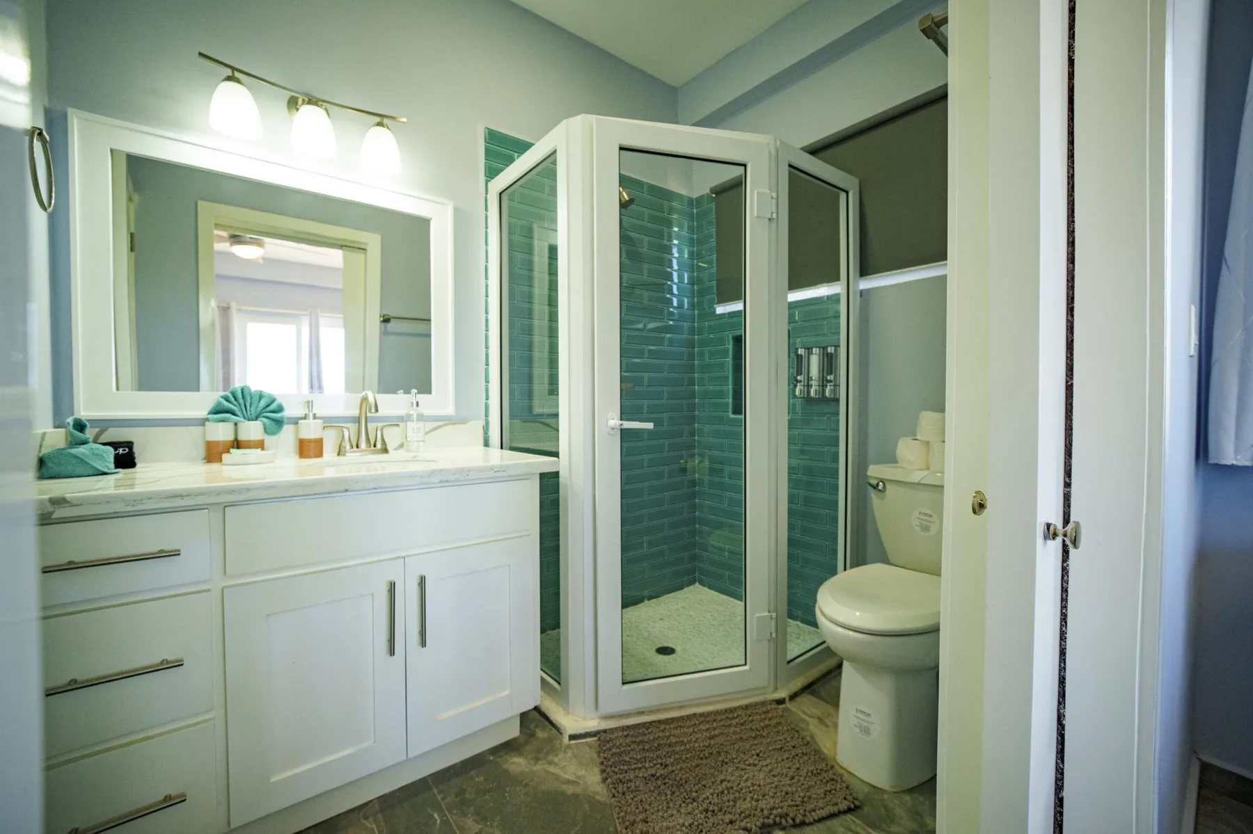 A bathroom with a glass shower, vanity, and toilet.