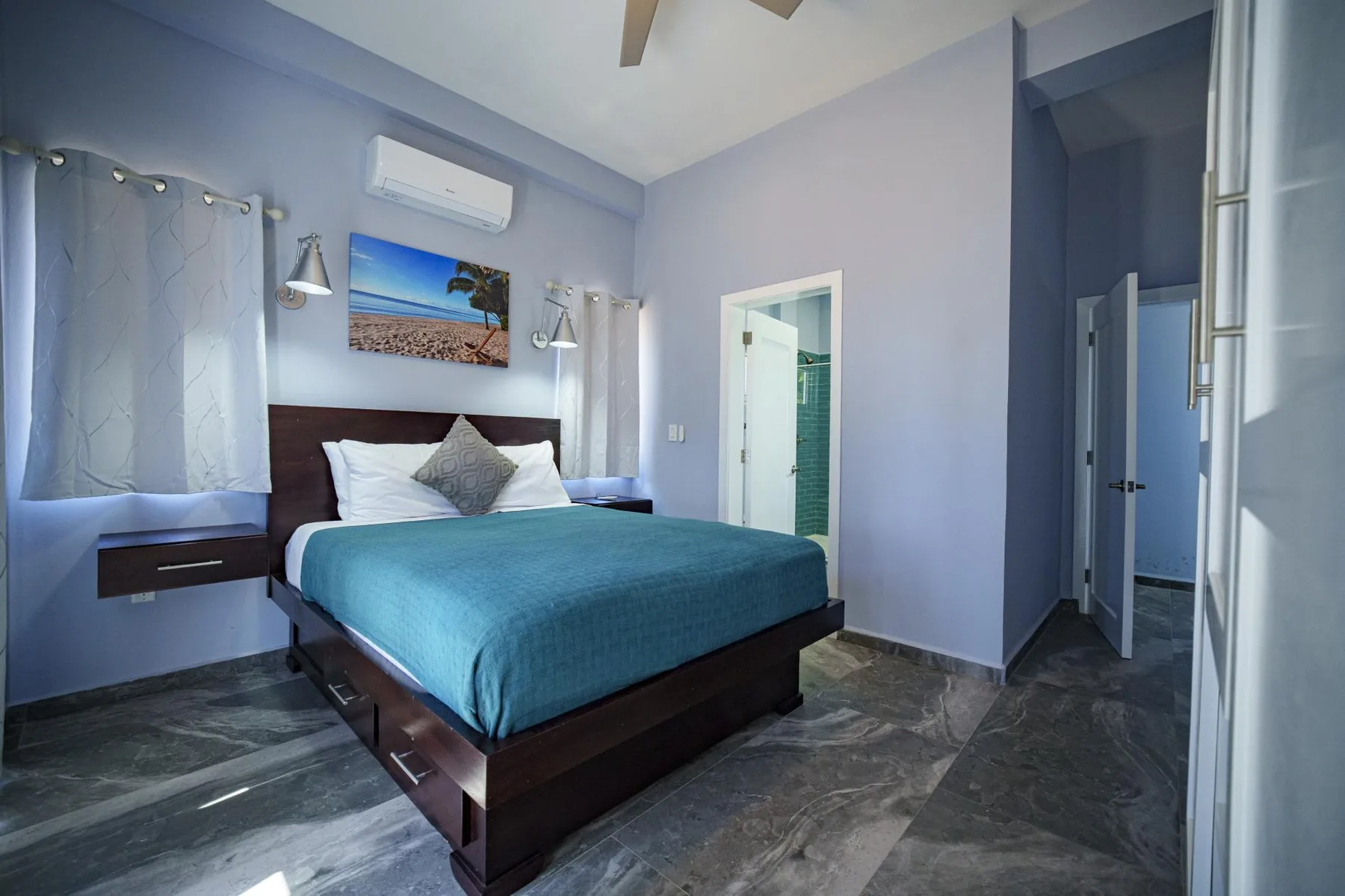 A bedroom with a bed, blue walls, and a doorway.
