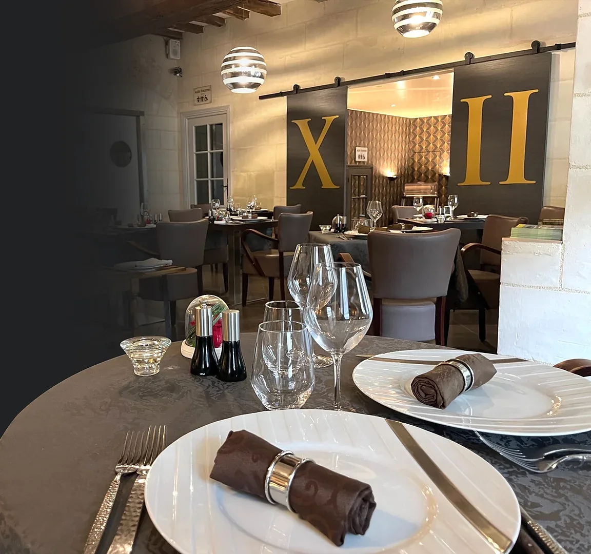 Espacio representativo del hotel: Un comedor con mesas preparadas, cristalería y lámparas colgantes.
