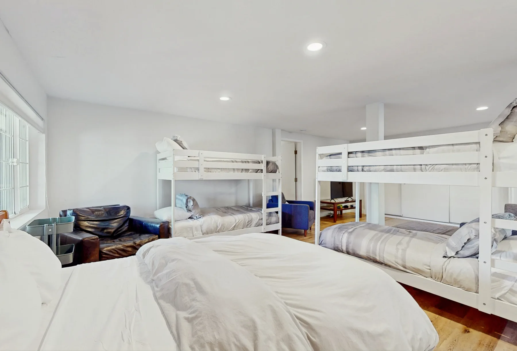 Un dormitorio luminoso con varias literas y ropa de cama blanca.