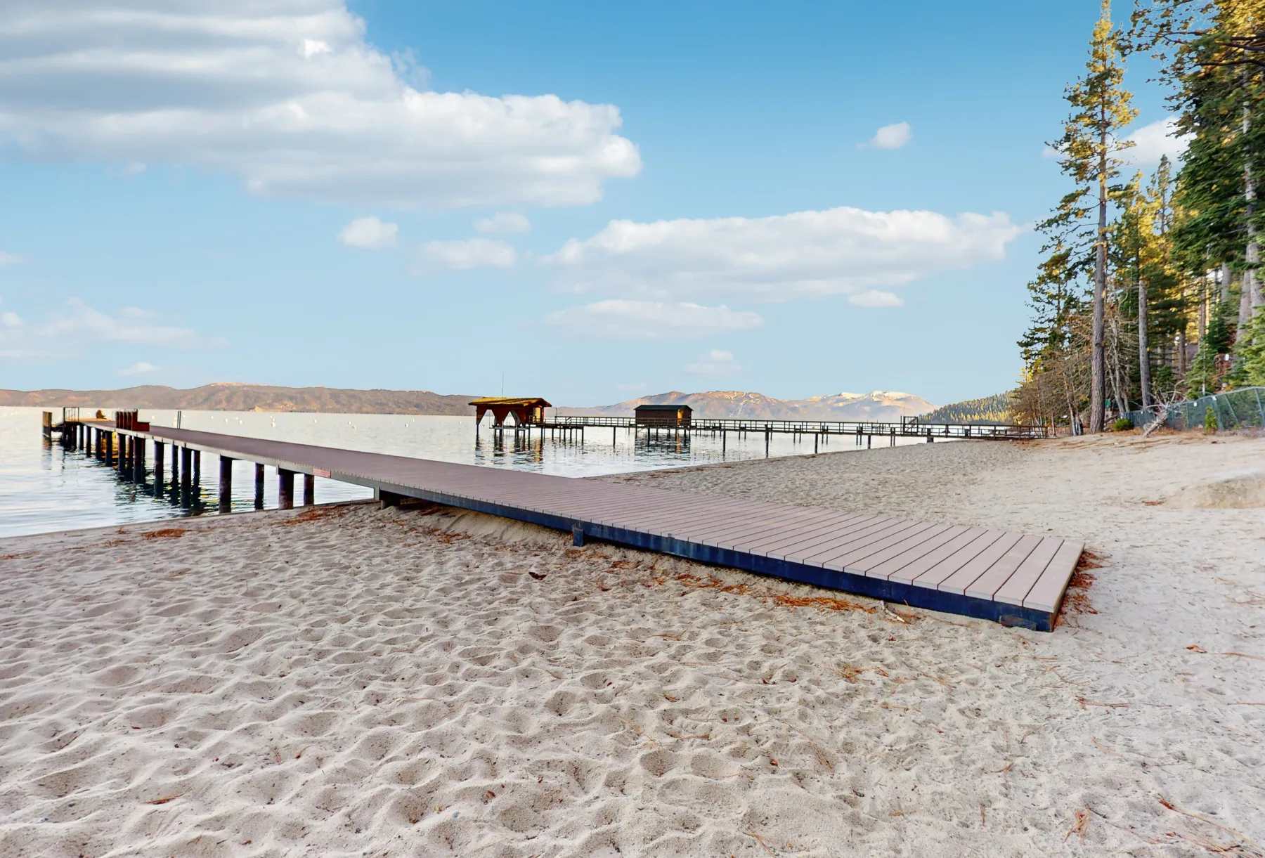 Zona común: Un muelle de madera se extiende junto a una orilla arenosa.