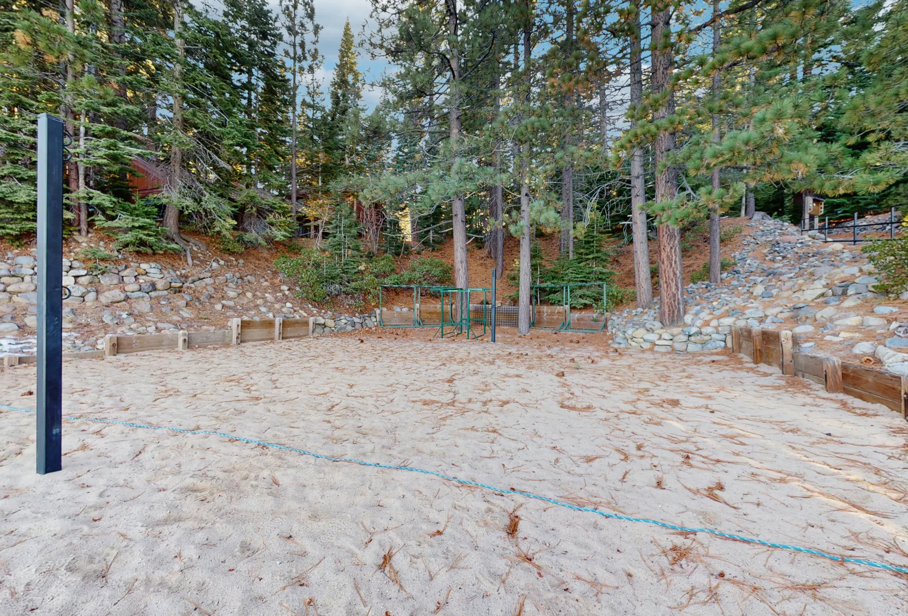 Zona común: Una zona recreativa al aire libre con arena, muros de piedra y árboles.