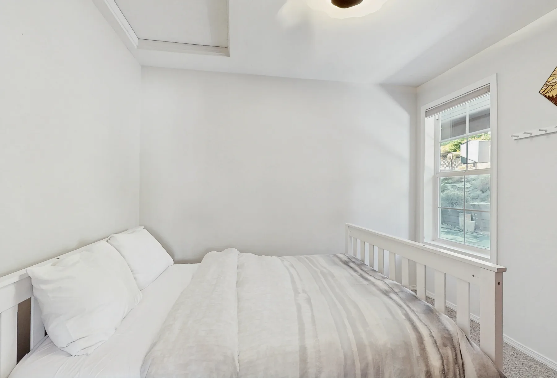 Un dormitorio luminoso con una cama junto a una ventana.