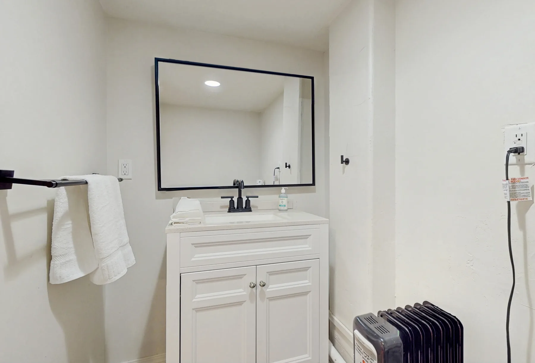 Un lavabo de baño con un espejo grande y toallas colgadas al lado.