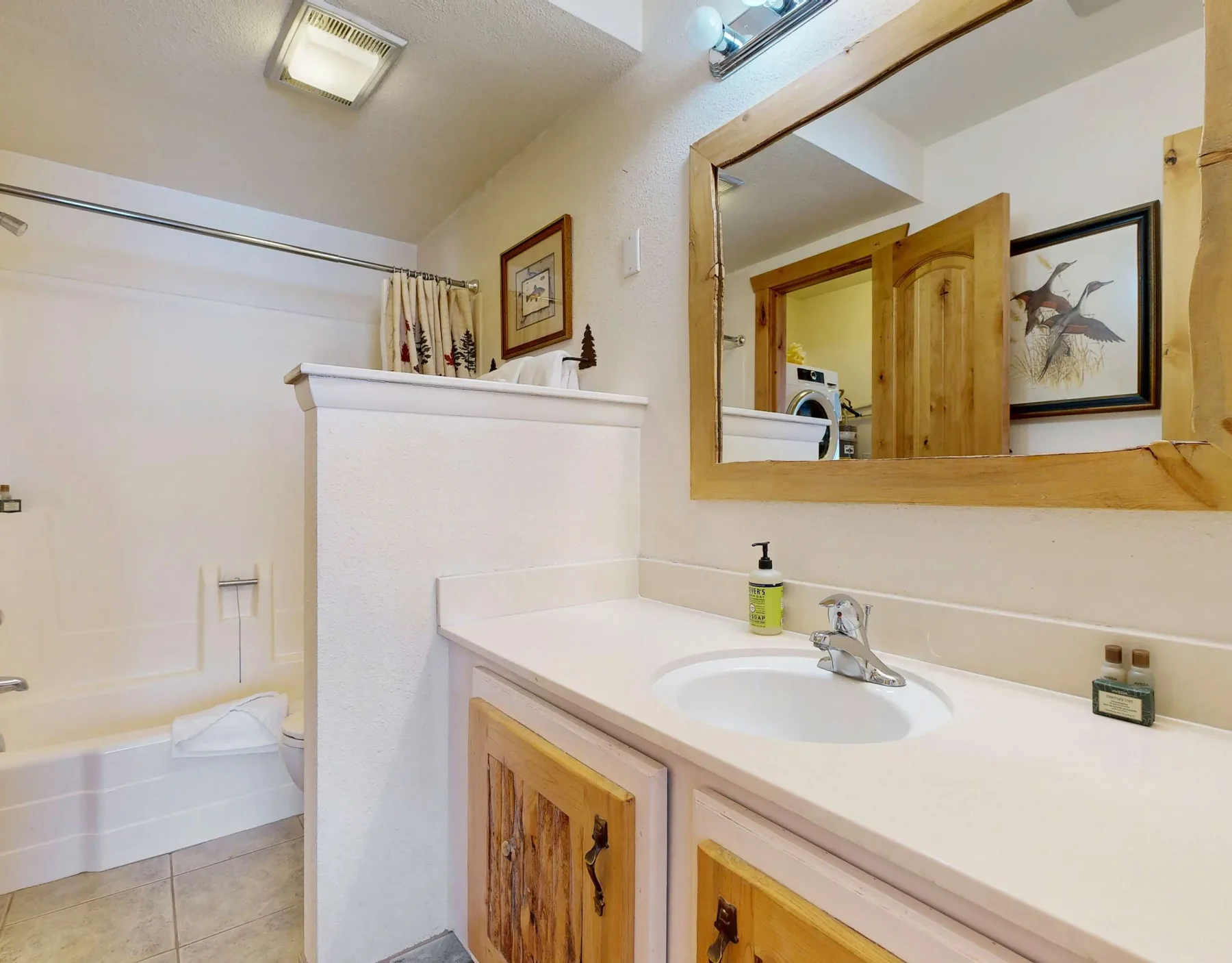 Un tocador de baño con lavabo y espejo da a una bañera.