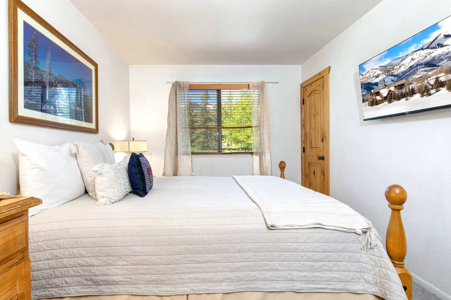 Un dormitorio con una cama bien tendida debajo de una ventana.