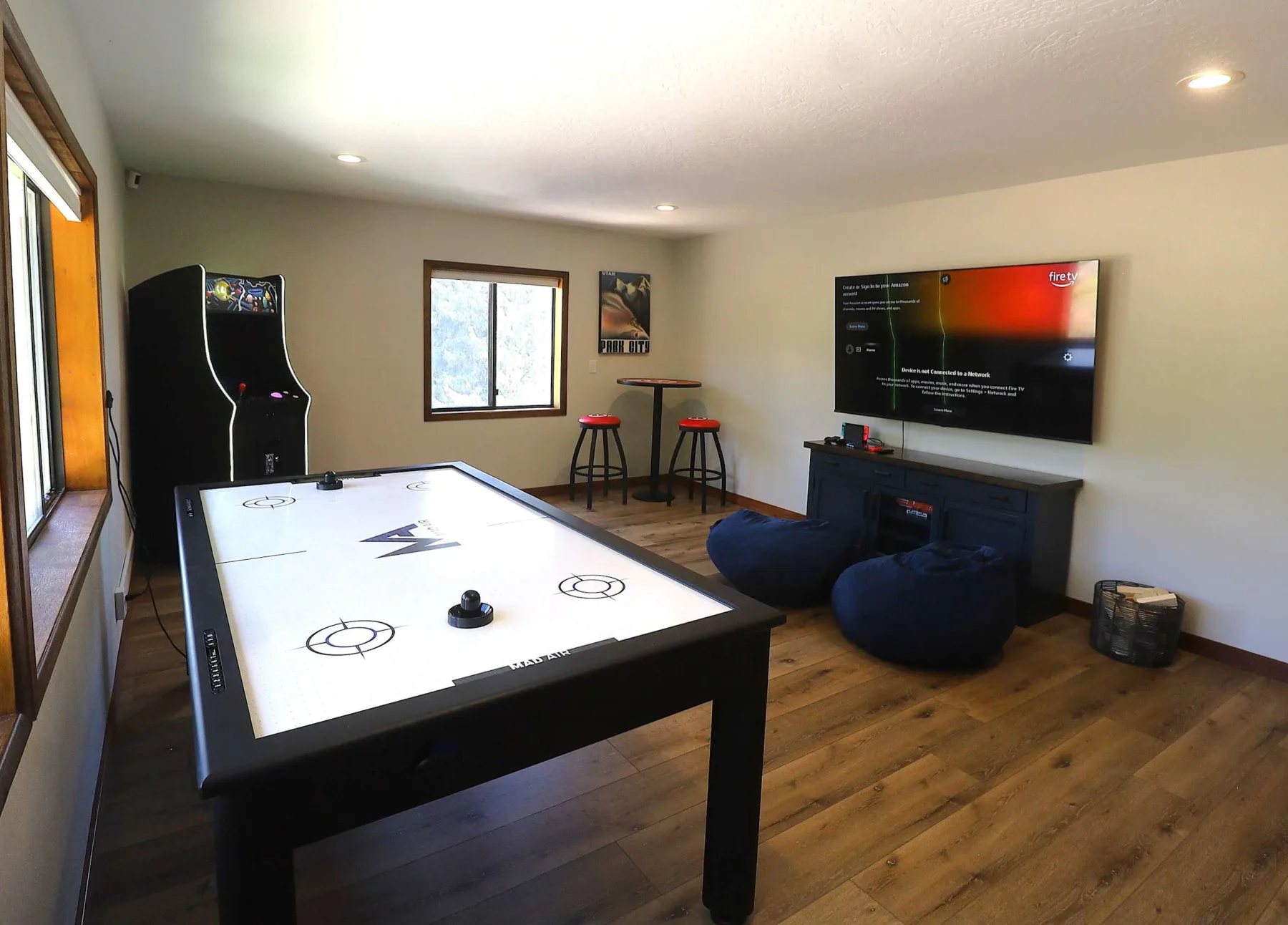Zona común: Sala de juegos con una mesa de billar, una máquina recreativa y un televisor en la pared.
