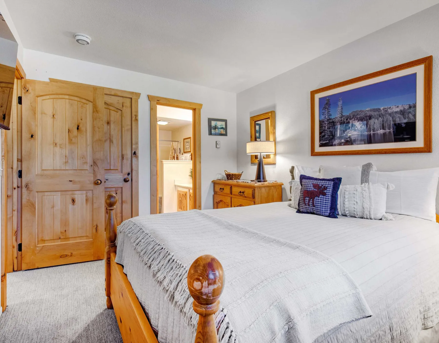 Un dormitorio con una cama bien tendida y puertas de madera.