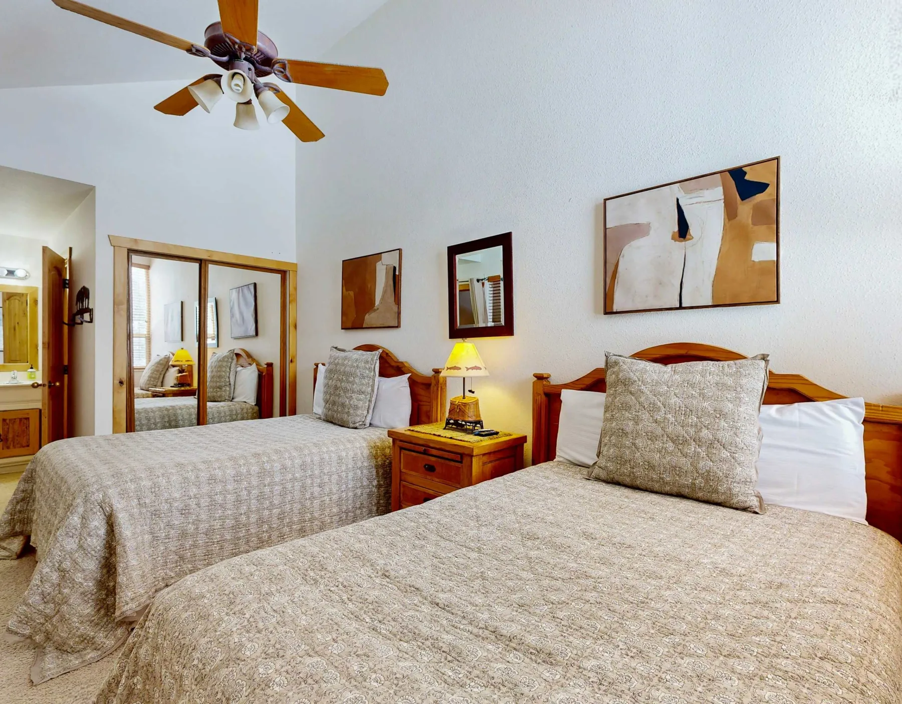 Un dormitorio con dos camas, mesitas de noche y cuadros enmarcados.