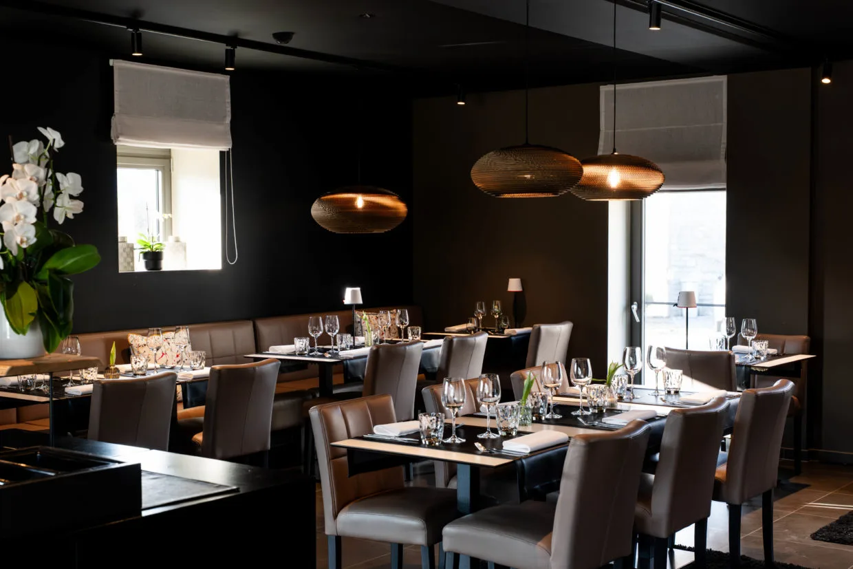 Representative hotel space: A restaurant dining room with tables set beneath pendant lights.