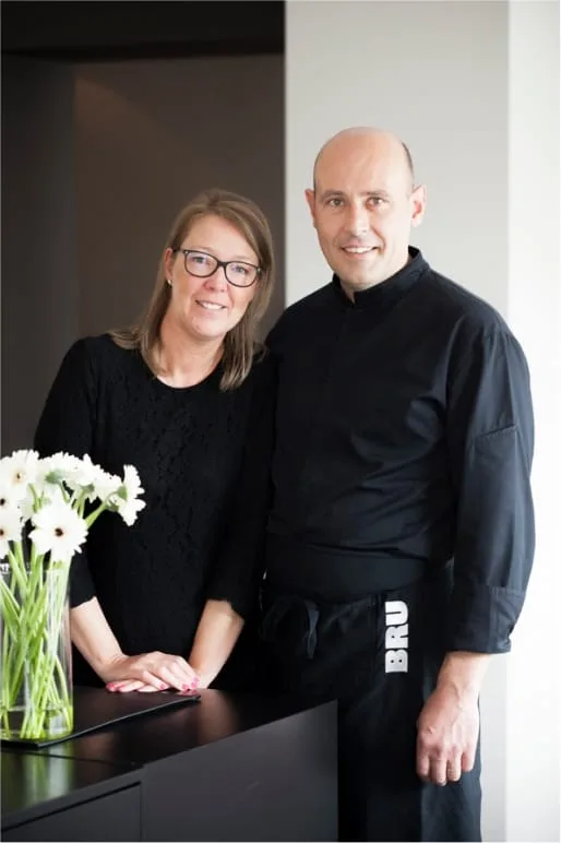 Representative hotel space: A woman and a man stand beside a counter with a vase of flowers.