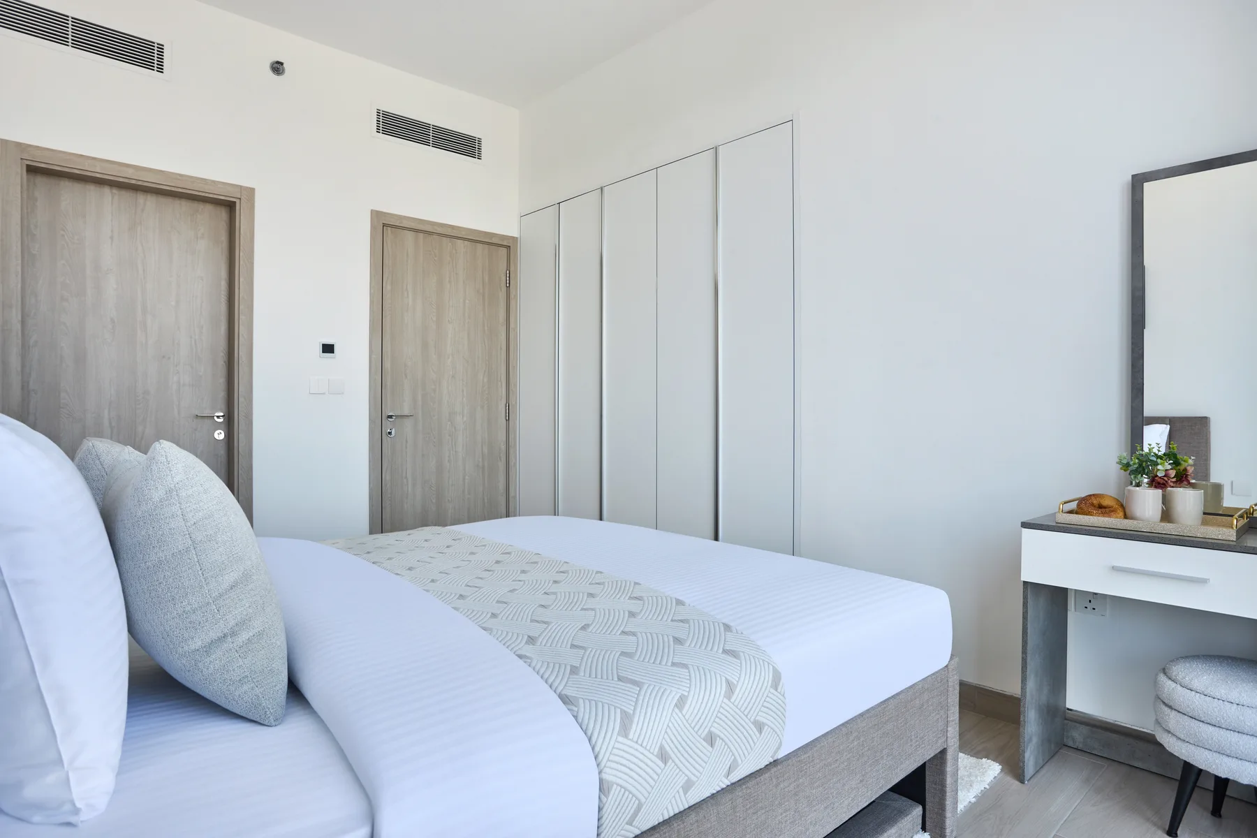 A bright bedroom with a neatly made bed and a small desk.