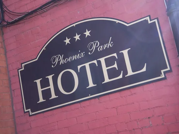 Espacio representativo del hotel: Un letrero del Phoenix Park Hotel está montado en una pared de ladrillo rojo.