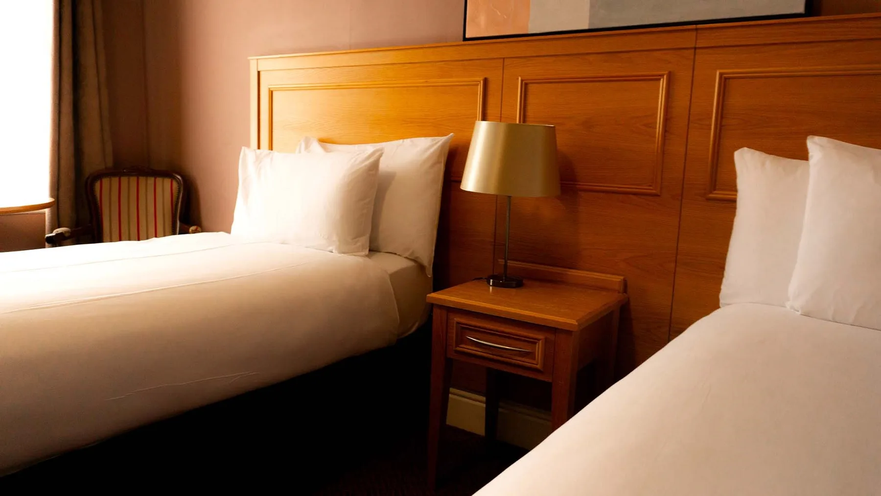 Espacio representativo del hotel: Un dormitorio de hotel con dos camas y una lámpara de noche.