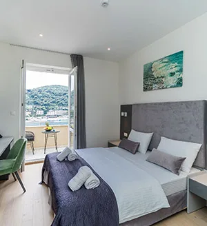 Representative hotel space: A bedroom with a made bed, bedside tables, and a balcony doorway.