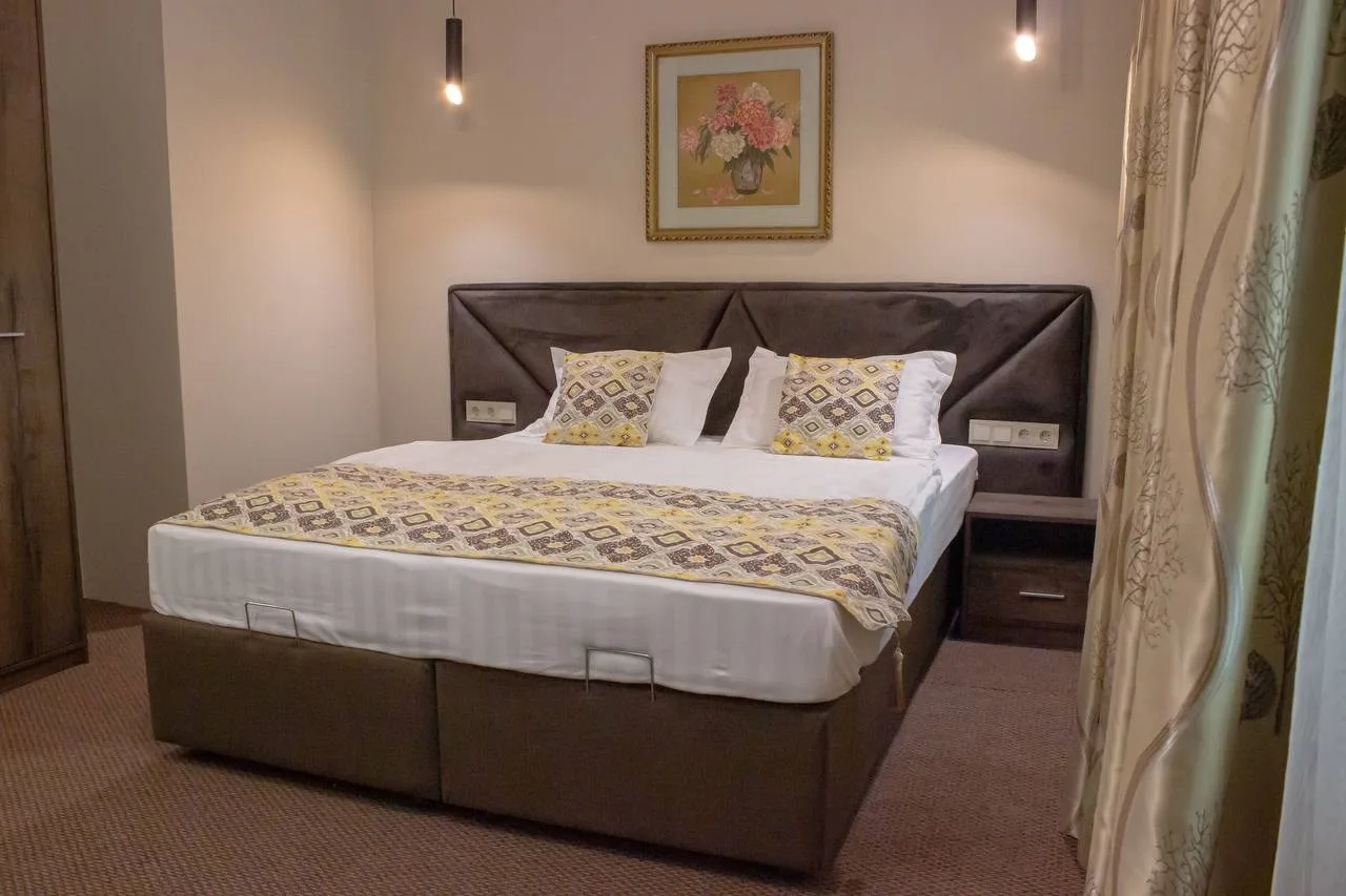 Espacio representativo del hotel: Un dormitorio con una cama doble, ropa de cama estampada y cortinas.