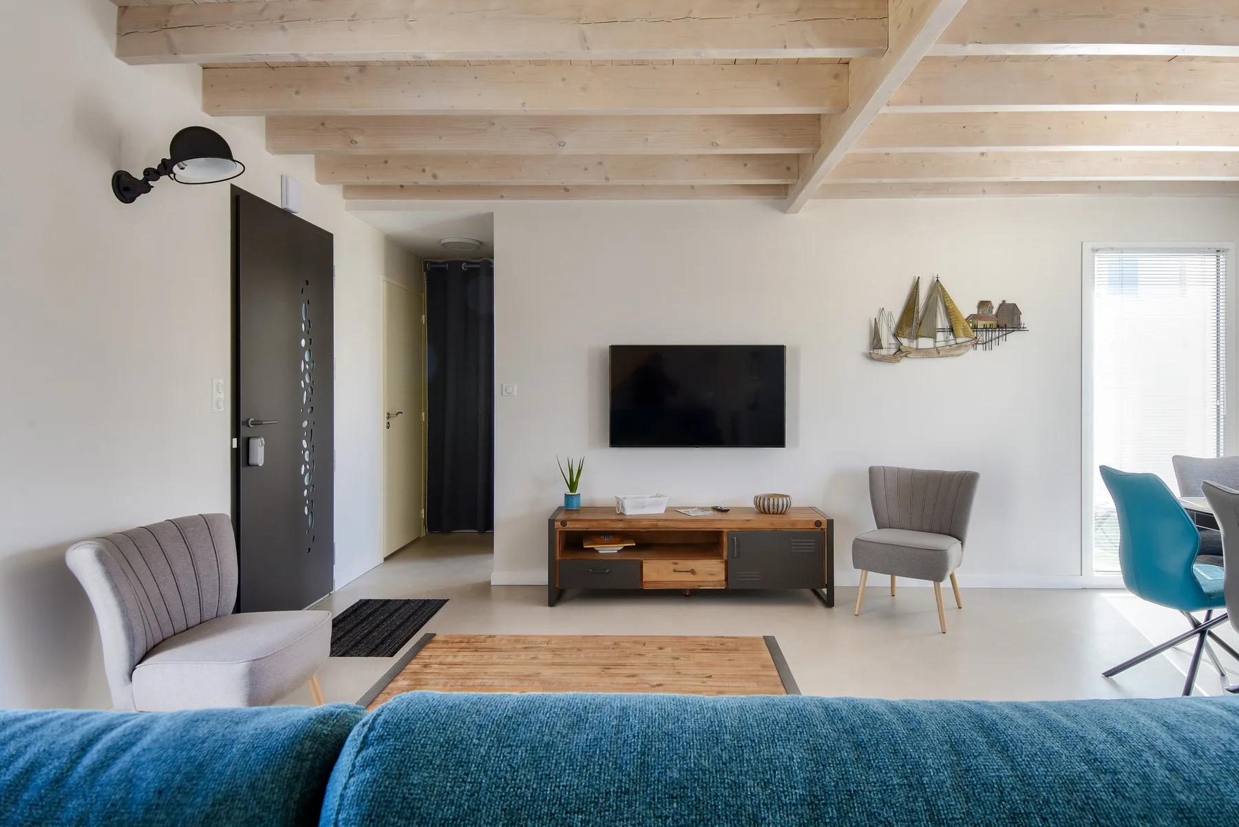 A bright living room with a wall-mounted television and seating.