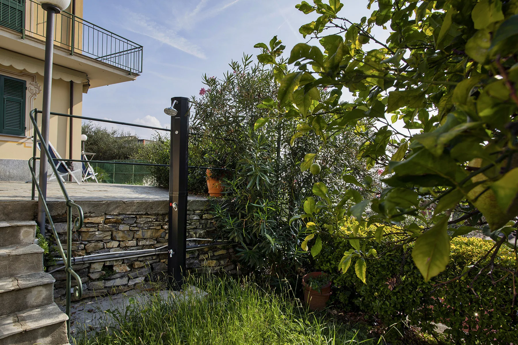 A garden with dense shrubs beside a house and a stone retaining wall.