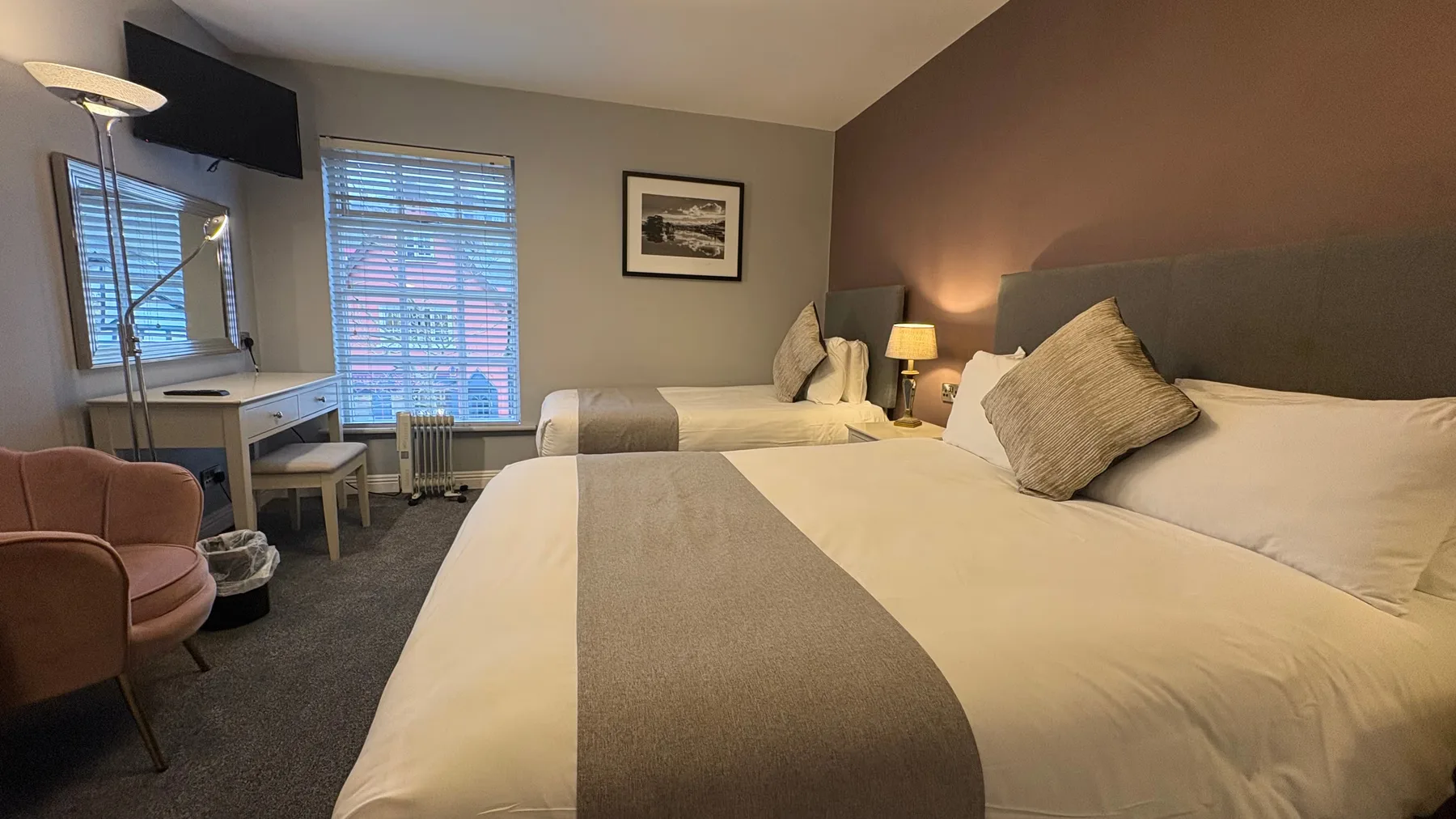 Espacio representativo del hotel: Un dormitorio con dos camas, un escritorio y una ventana con persianas.