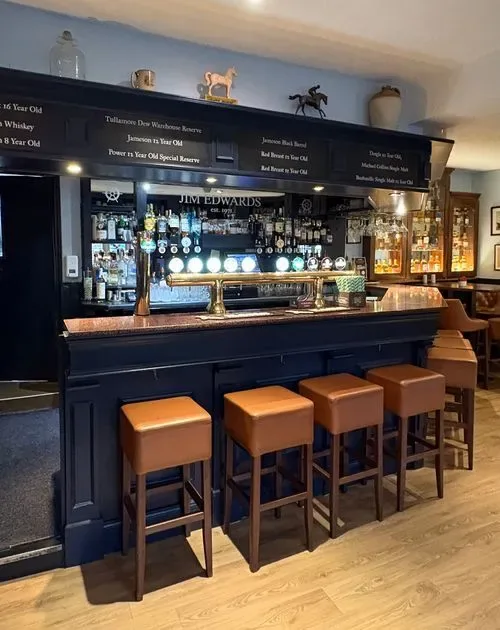 Espacio representativo del hotel: Una barra de pub con taburetes y botellas expuestas detrás del mostrador.