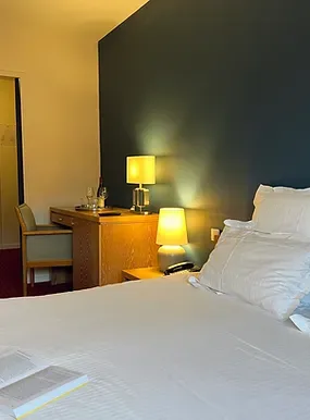 Espacio representativo del hotel: Un dormitorio de hotel con una cama tendida y lámparas de mesilla.