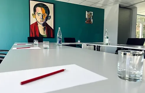 Espacio representativo del hotel: Una sala de reuniones con mesas blancas, papeles y botellas de agua.