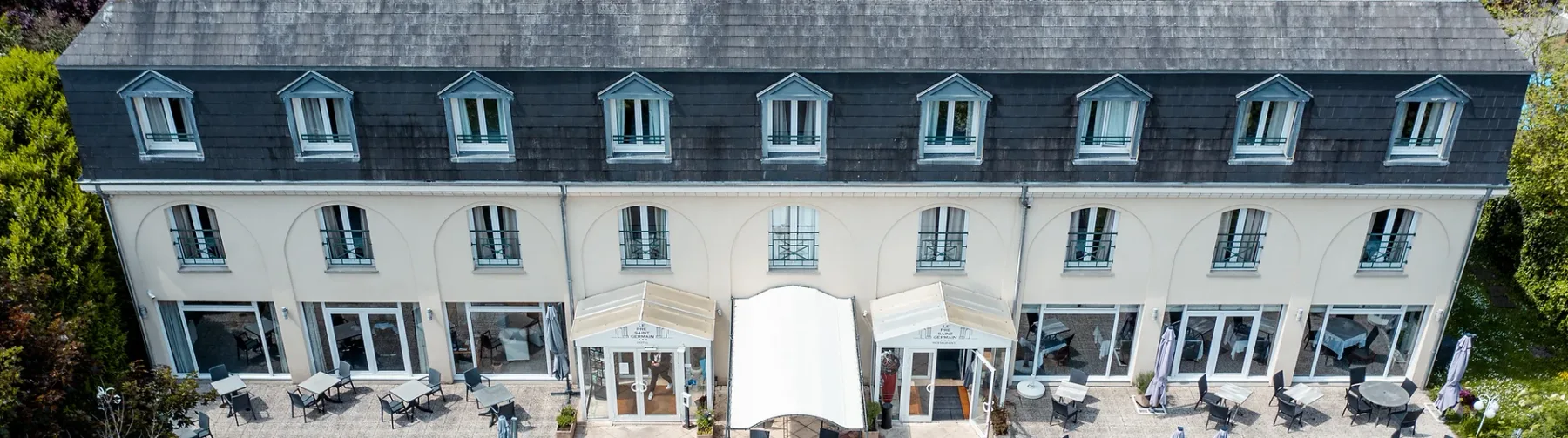 Espacio representativo del hotel: Una larga fachada de hotel con filas de ventanas y asientos al aire libre en la planta baja.