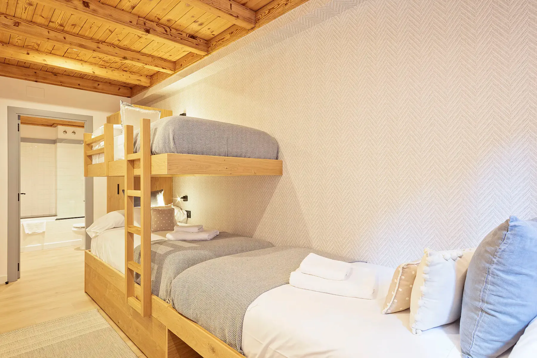A bedroom with a wooden bunk bed and light bedding.