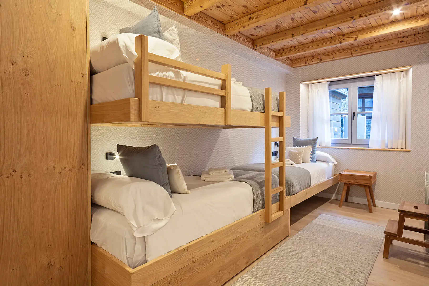 A bedroom with wooden bunk beds and a window.