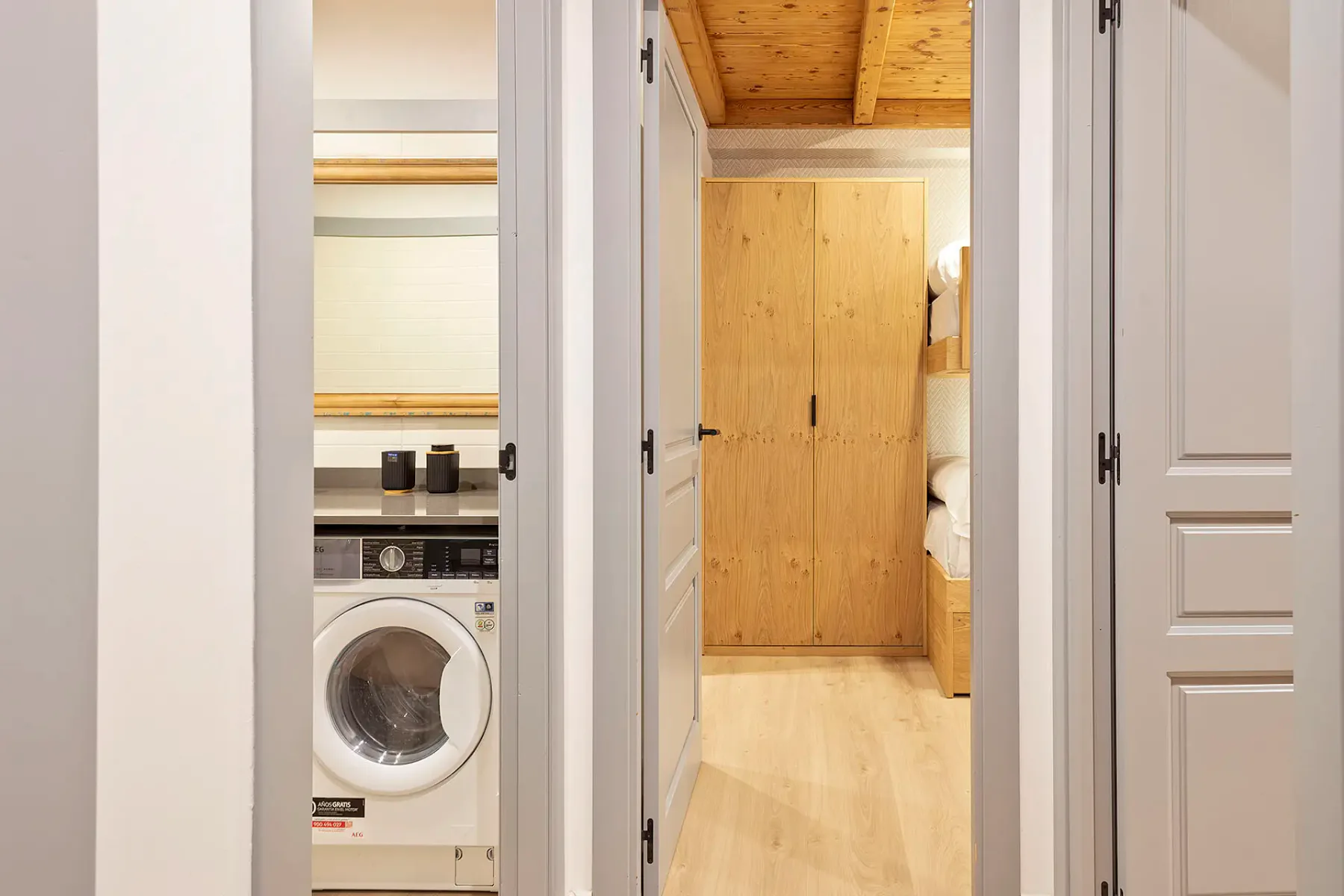 A hallway opens onto a bedroom, with a washing machine visible in an adjoining laundry area.