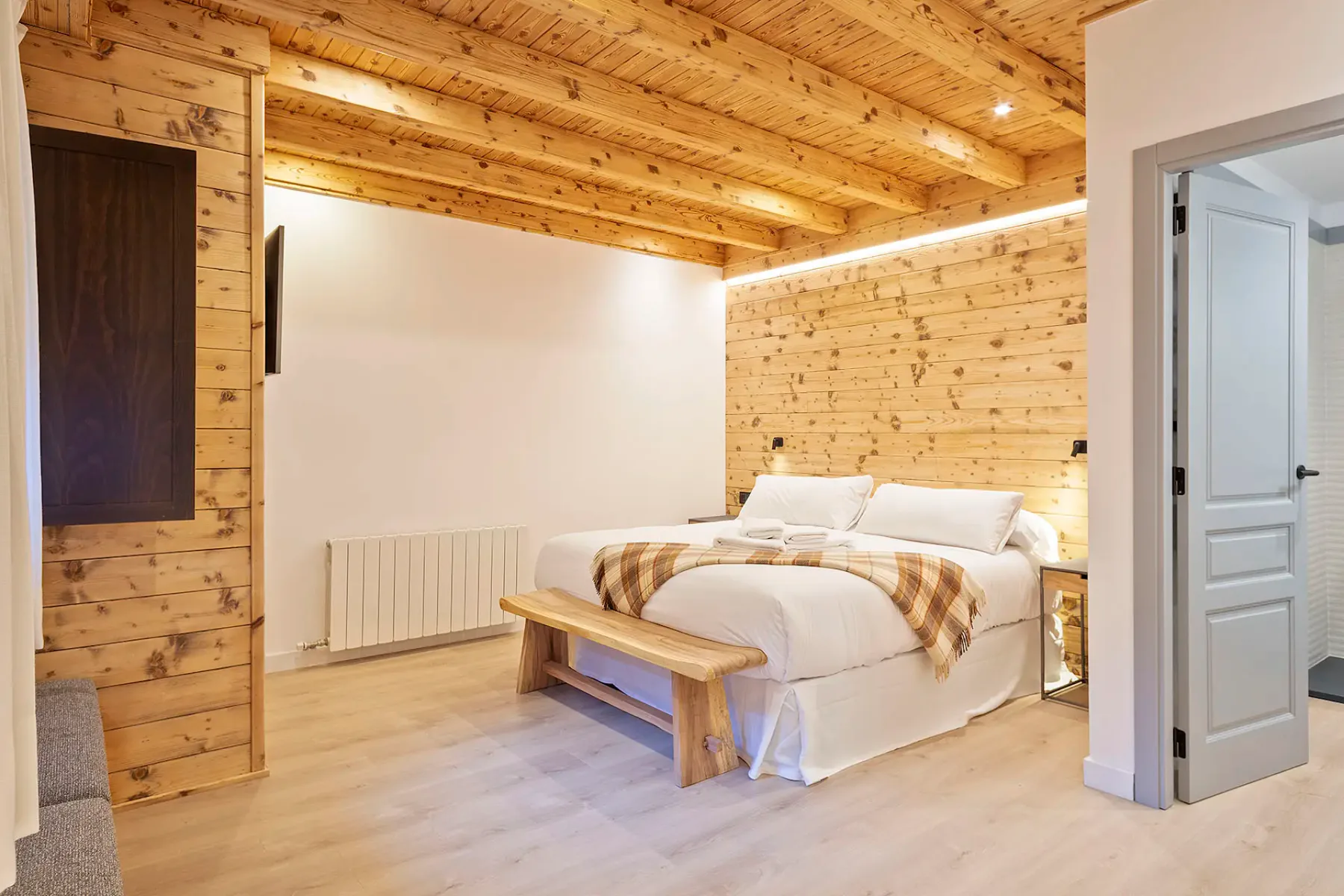 A bedroom with a bed and wooden walls and ceiling.