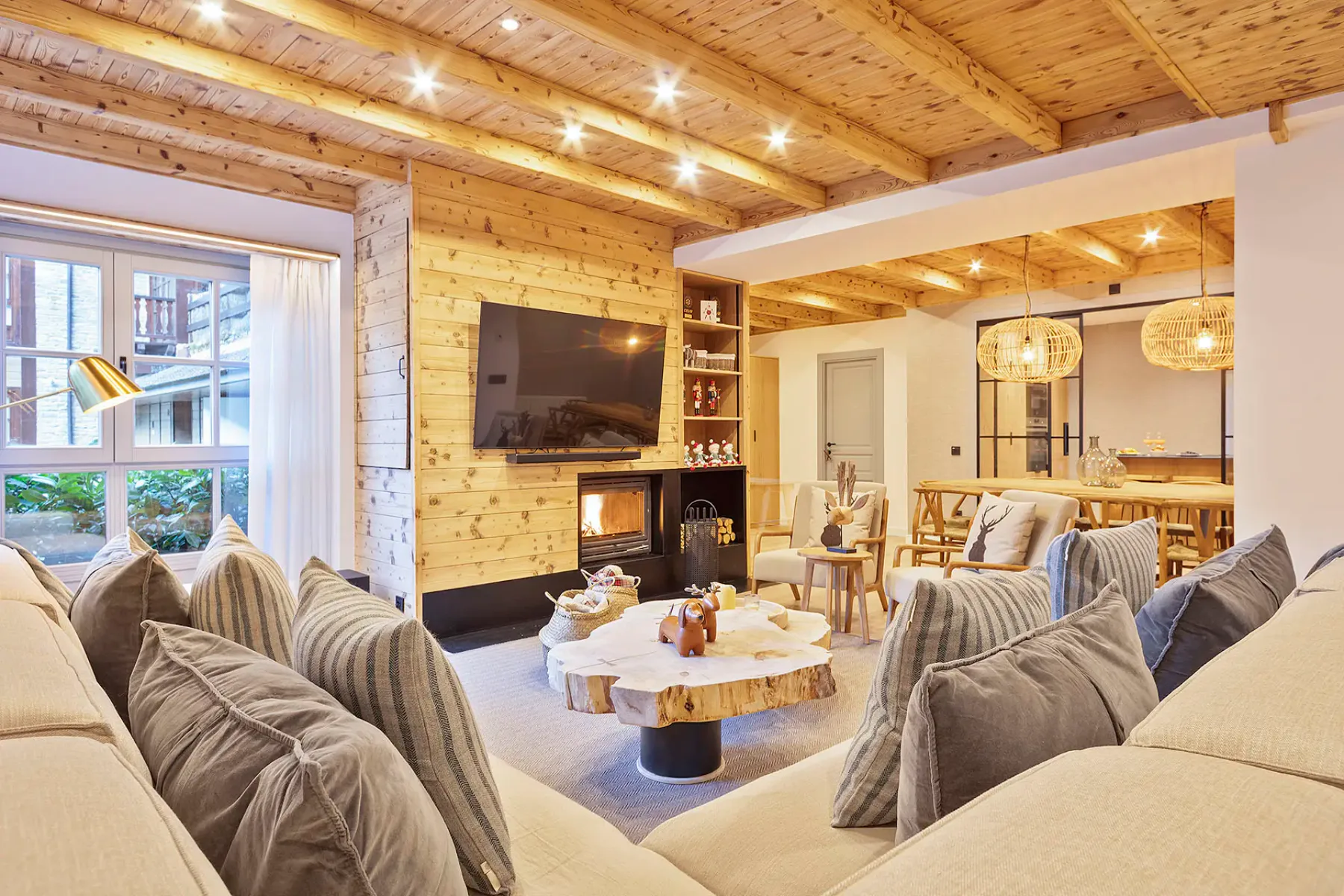 A warmly lit living room with seating around a low coffee table and a fireplace.