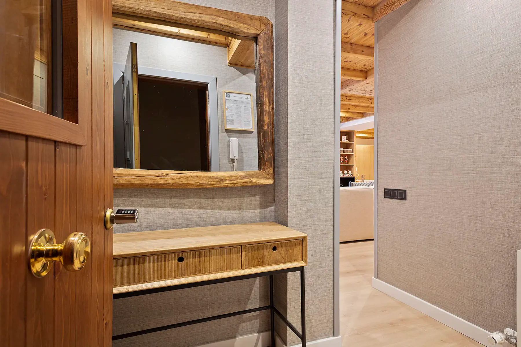 A wood vanity with a large mirror sits beside an open doorway.