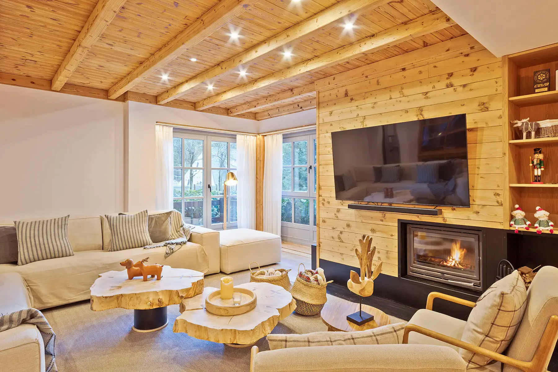 A living room with seating around a coffee table and a fireplace beneath a television.