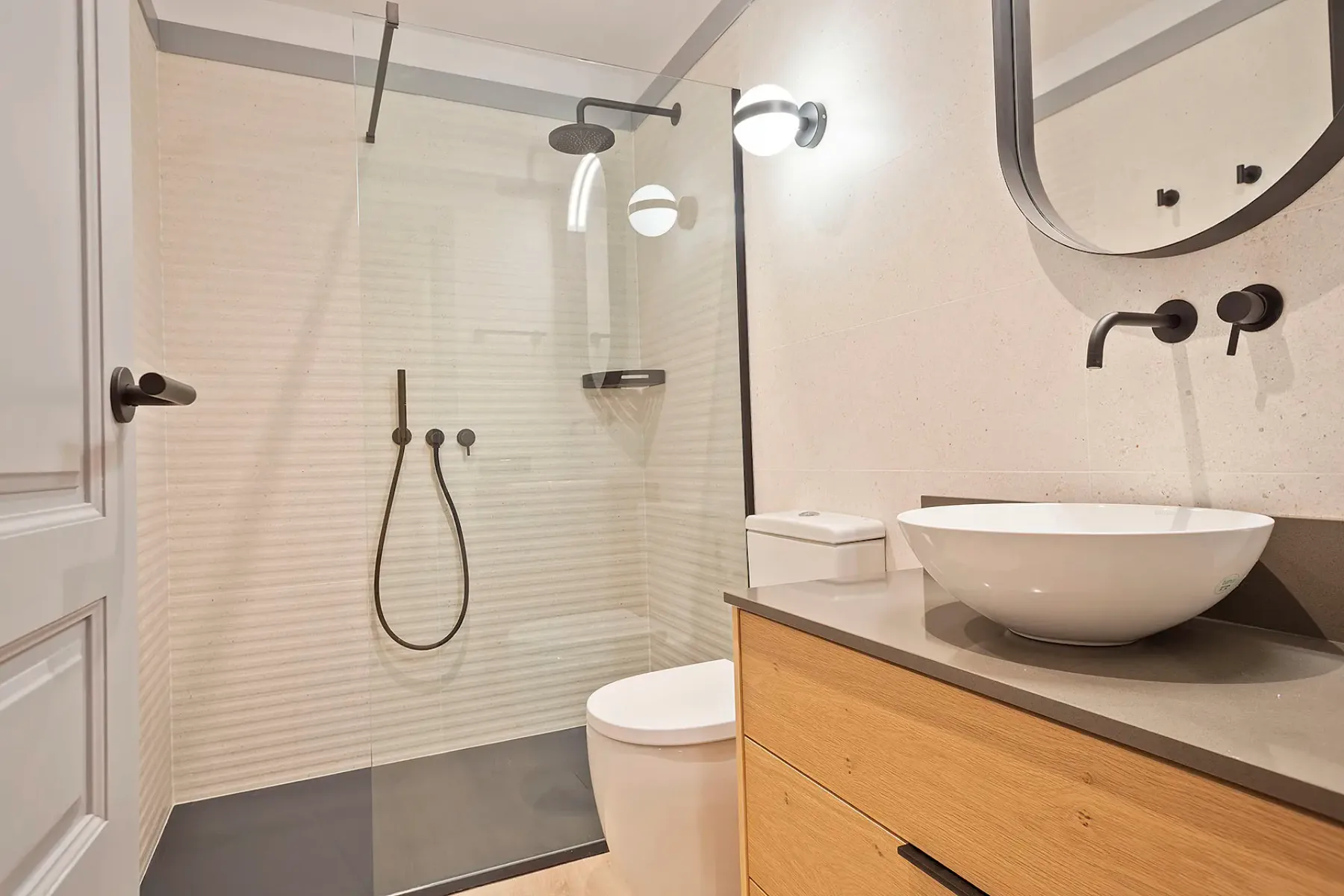A bathroom with a glass shower, toilet, and vessel sink.