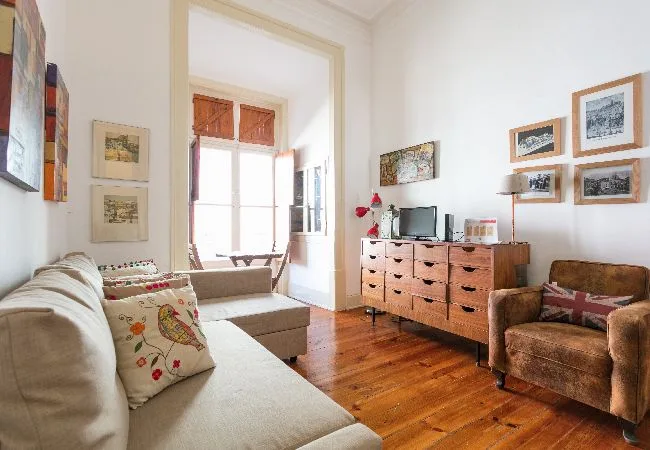 A bright living room with seating, a wooden dresser, and framed artwork.