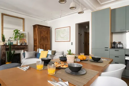 Comedor con la mesa puesta y una zona de estar al fondo.